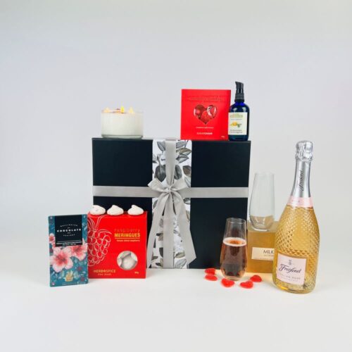 The Indulge Gift Hamper includes a bottle of Freixenet sparkling Italian Rose, two stemless flutes, a bottle of massage oil, gummy heart lollies, a stunning three wick candle, raspberry meringues and a bar of Wellington Chocolate Factory chocolate. All contained in a luxury gift box. Gifts for You & Me